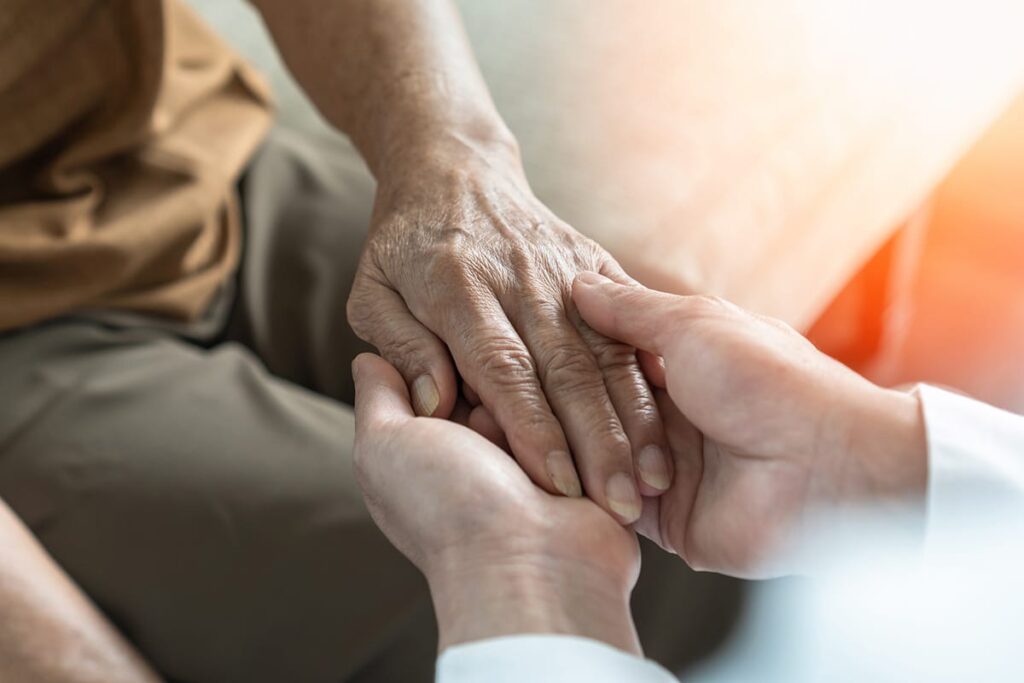 a person holds another's hands after explaining the benefits of assisted living