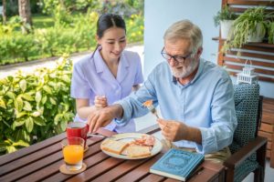 young woman helping older man at the dinner table as one of the 5 benefits of assisted living in texas