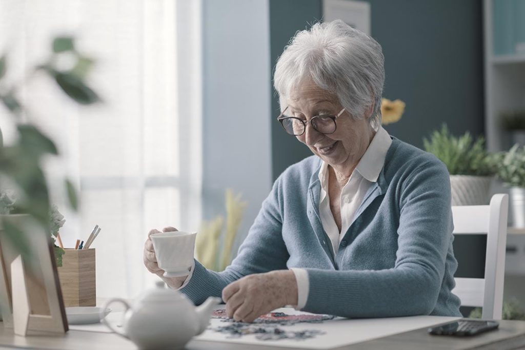 elderly woman happily reading about how your loved one can benefit from memory care services