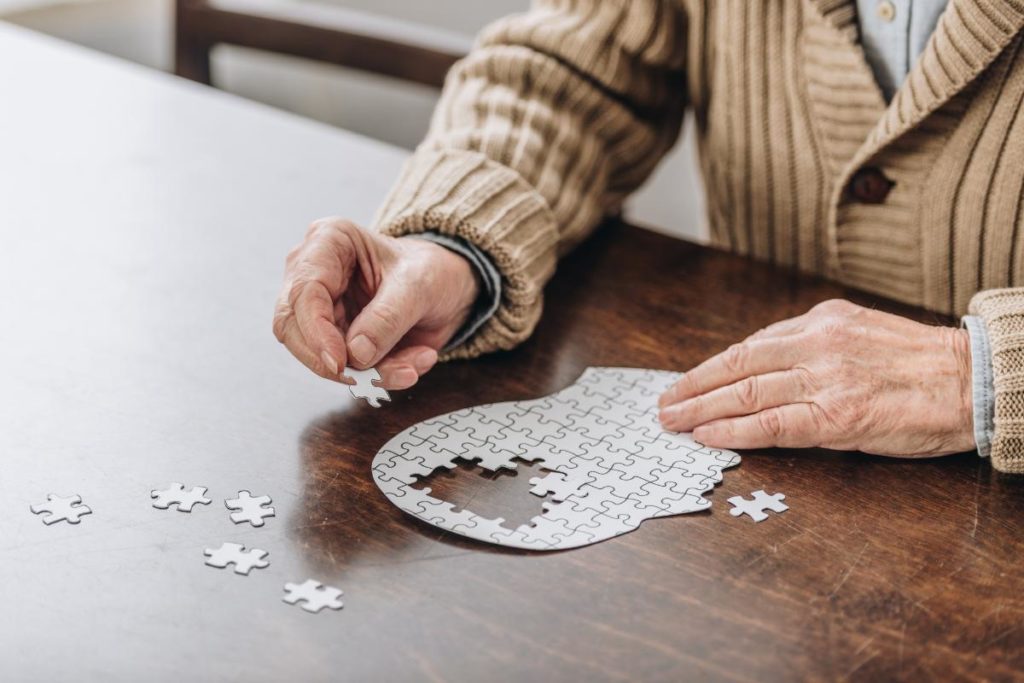 senior living resident working a puzzle at a table employing one of the 5 easy ways to improve a seniors memory