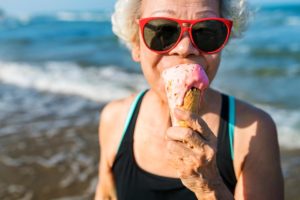 elderly woman eating an ice cream cone at the beach on a sunny day experiencing the power of ice cream on alzheimers