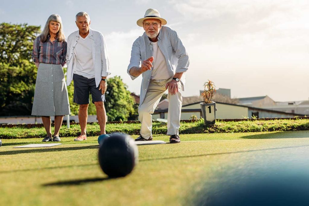 older couple watching older man play bocce ball as one of the fun and safe senior outings for any time of year