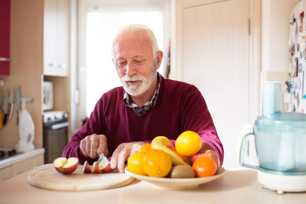 senior male sitting at kitchen table with bowl and plate full of anti aging brain foods for seniors
