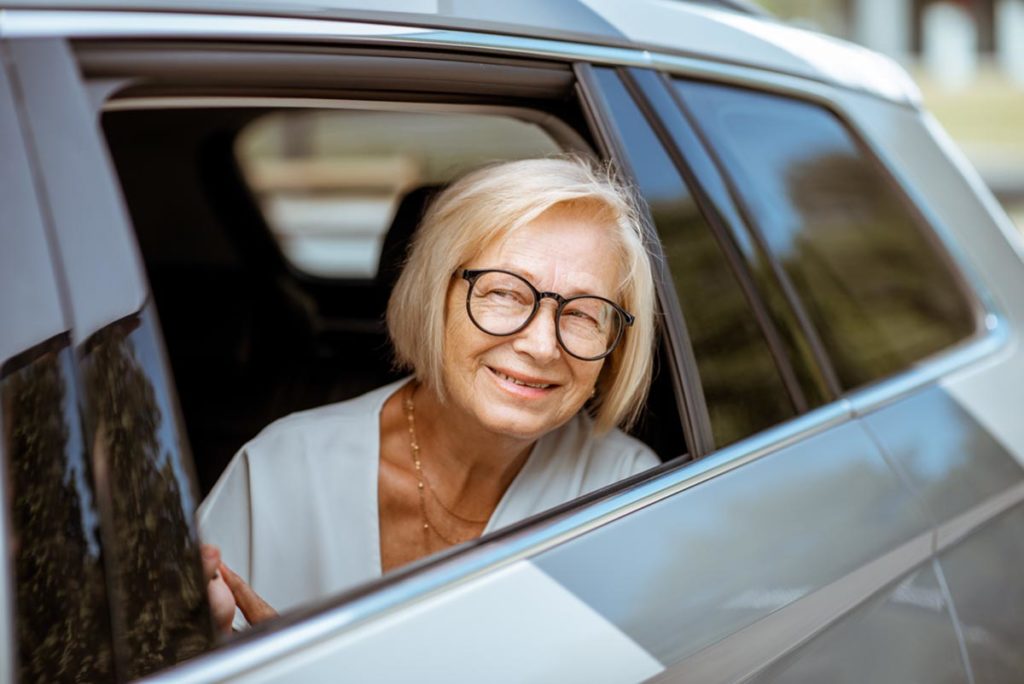 Senior woman sitting in car, using transportation services