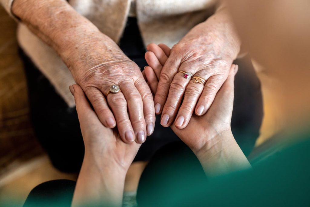 Nurse holding hands with elderly woman in respite care