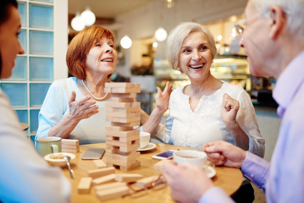 group of senior citizens sitting around a table playing games and engaging in one of 5 wellness activities for senior citizens
