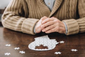 close up of senior adult working jigsaw puzzle while asking what's the difference between Alzheimer's and dementia