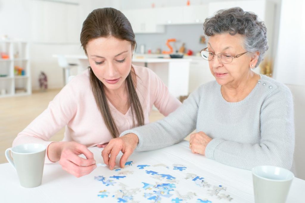 female memory care specialist working with elderly woman on 5 easy activities for elderly with dementia