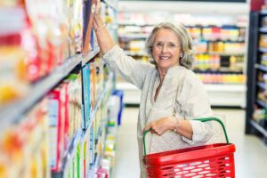 female senior citizen shopping in grocery store and staying mindful of the 10 foods elderly should avoid