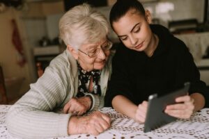 an adult child helps their parent with dementia read a tablet