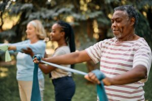 a group uses resistance bands outdoors, one of many outdoor exercises for senior citizens