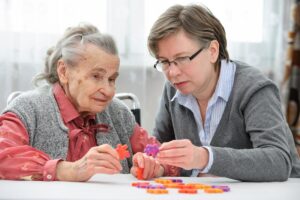 an adult child plays a tile game with a senior showing early signs of dementia