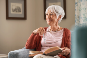 a senior smiles holding a book while wondering "what is senior independent living?"