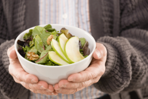 a senior man holds a bowl of healthy food